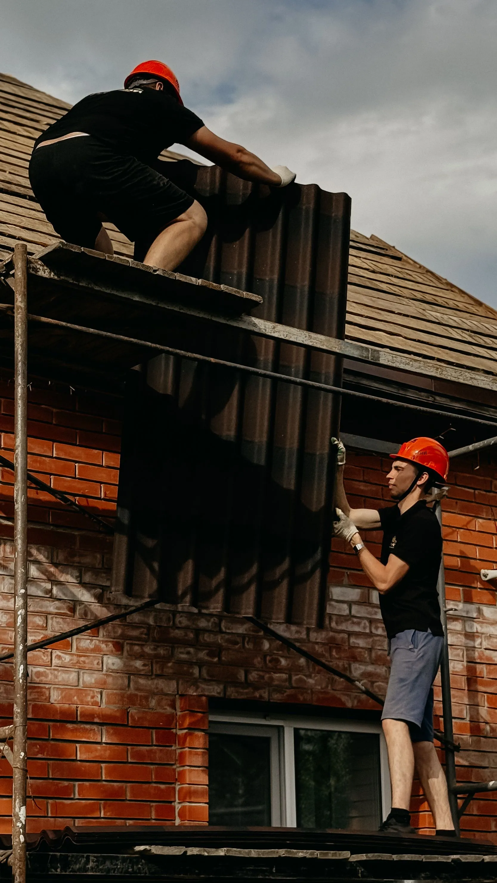 A worker in a hard hat at the wall of a house under scaffolding