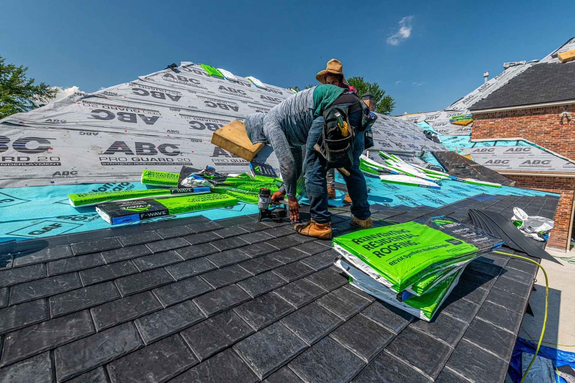 Roofers moving rolls of underlayment across a prepared roof slope