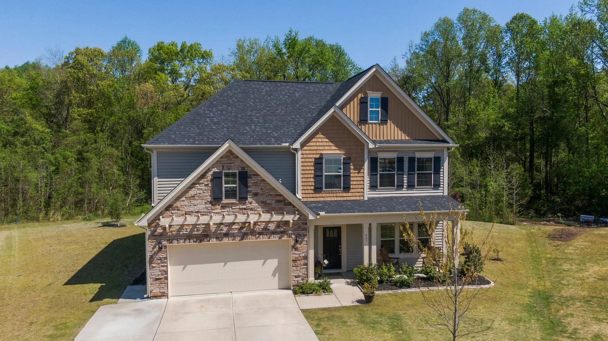 A two-storey suburban house with a shingled roof and a front lawn