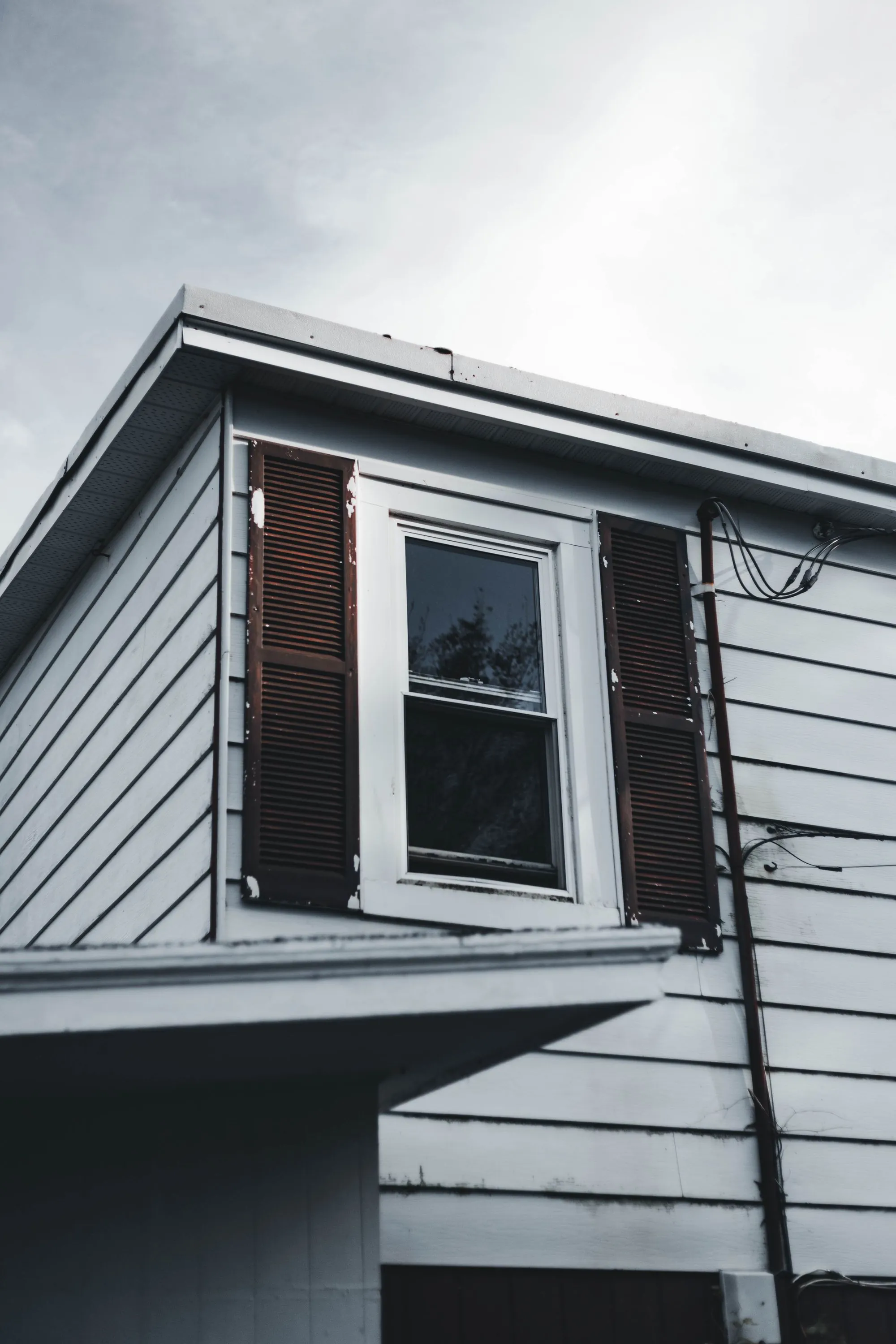 White siding and a shuttered window on the side of a house